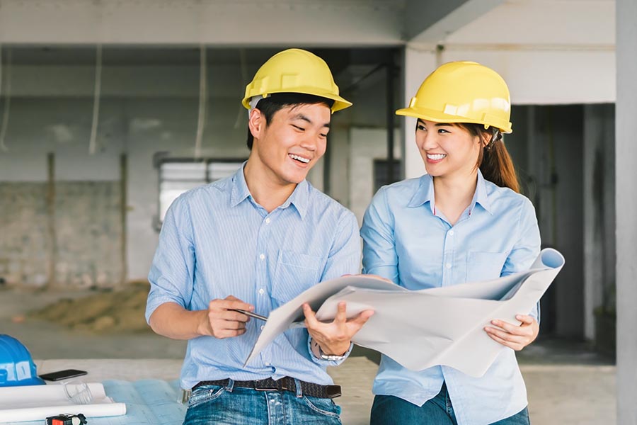 Specialized Business Insurance - Contractors Review Plans in a Large Unfinished Office Space, Wearing Hard Hats